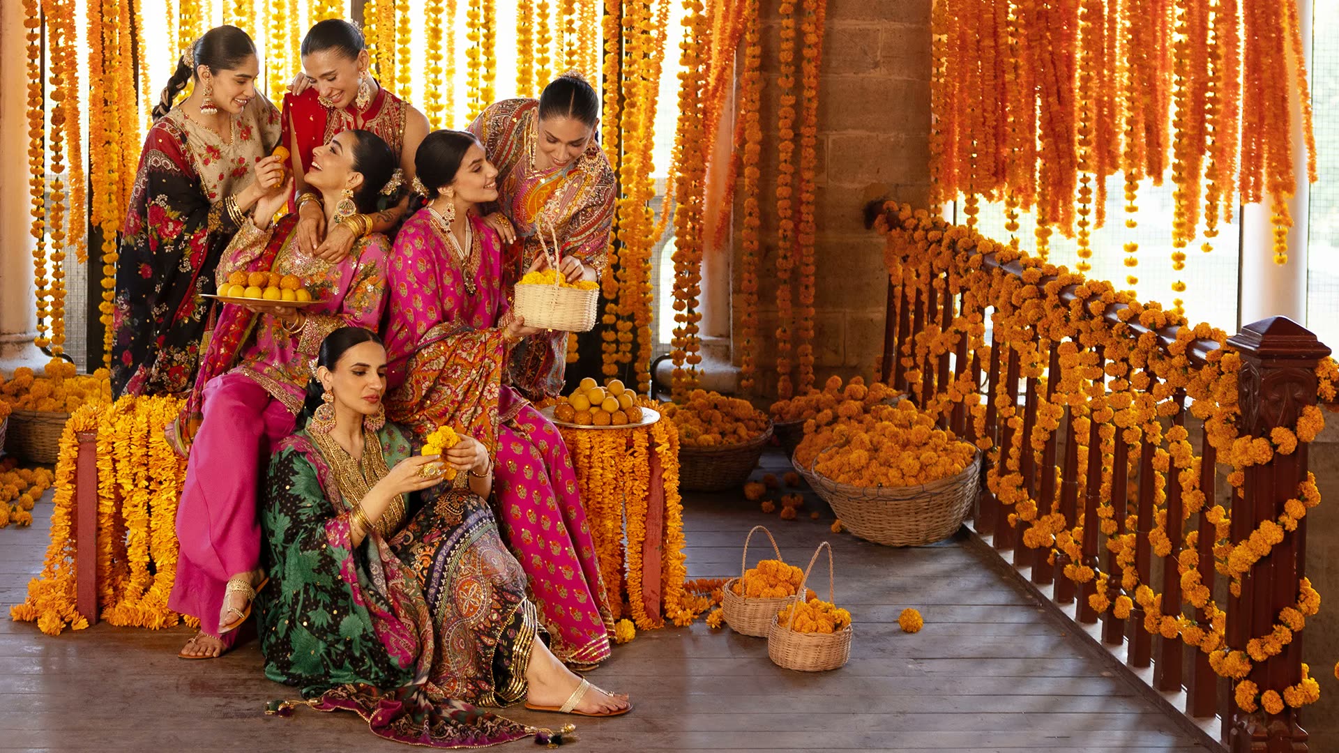 Women in embroidered Pakistani outfits celebrating amid marigold garlands